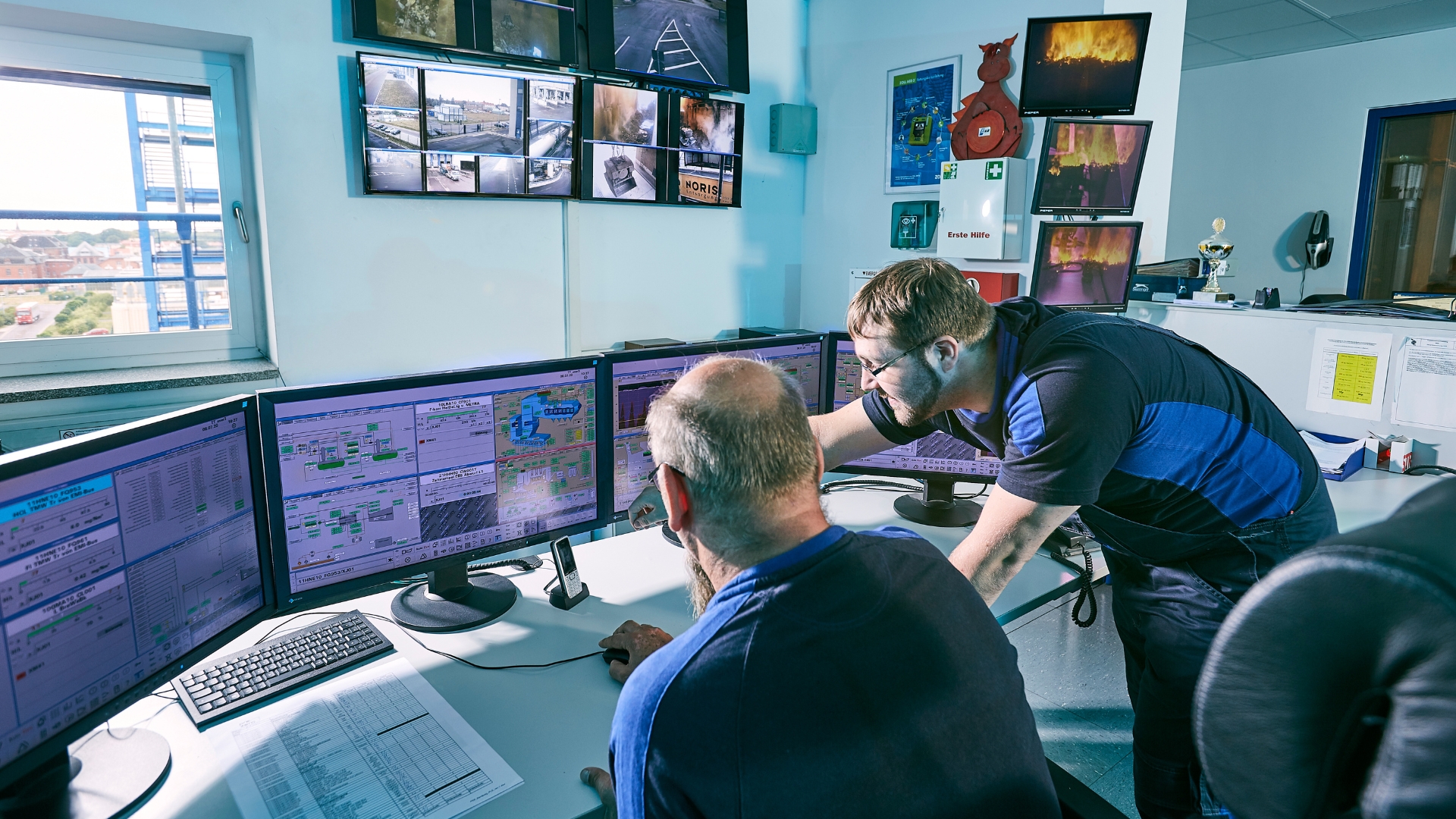 Blick auf zwei Männer, die über Bildschirme gebeugt sind