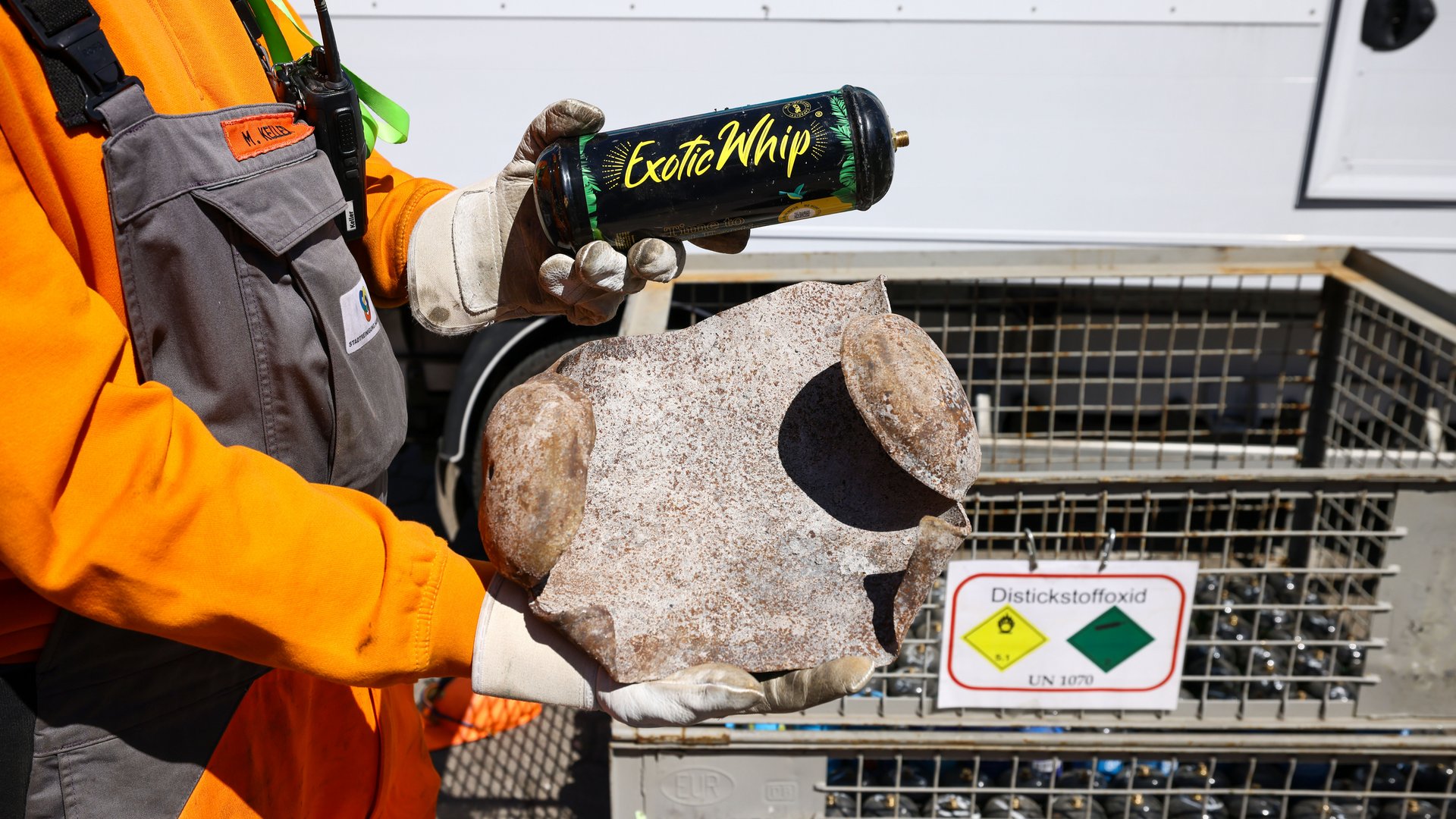 Ein Stadtreiniger hält eine explodierte Lachgas-Kartusche in der Hand