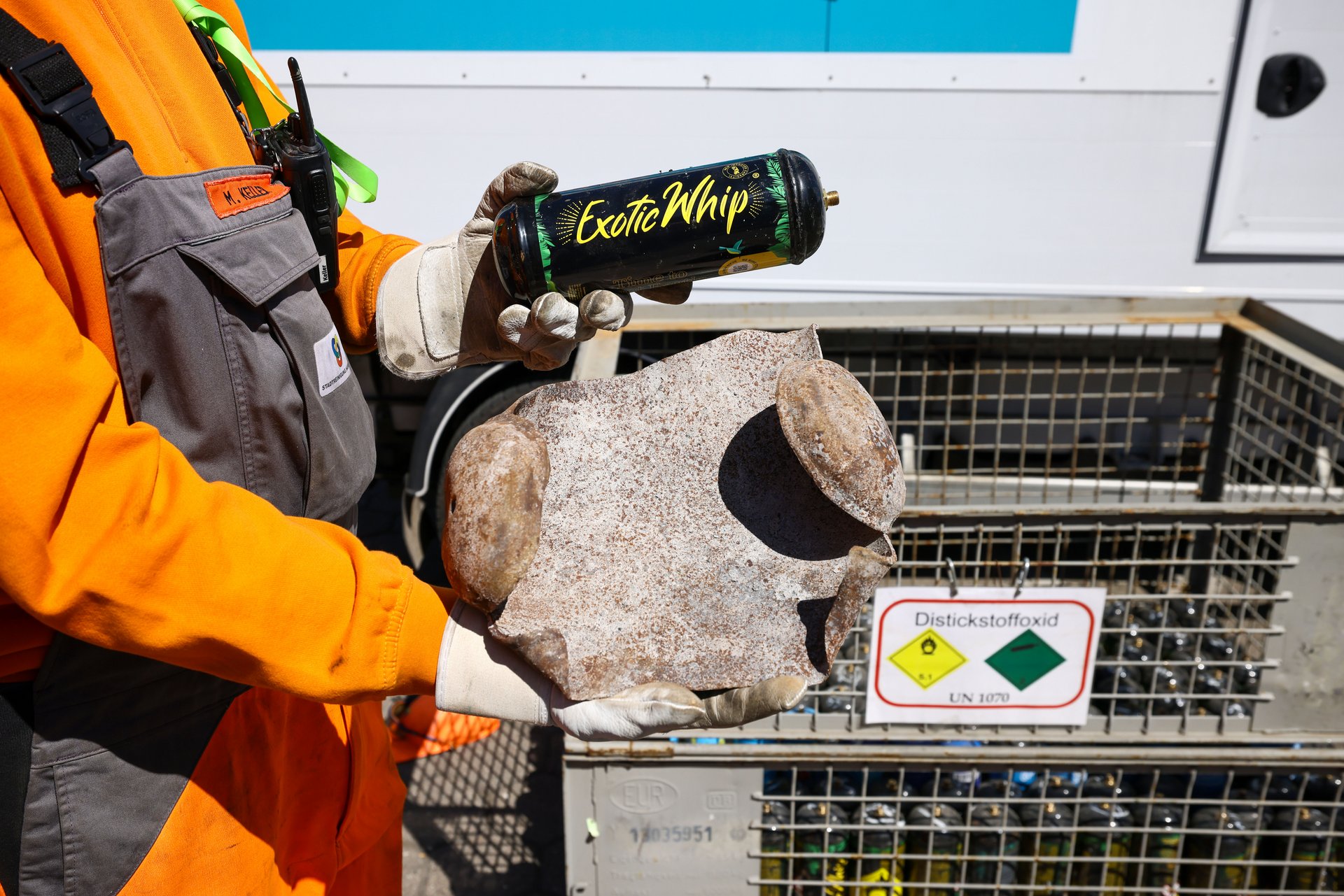 Ein Stadtreiniger hält eine explodierte Lachgas-Kartusche in der Hand