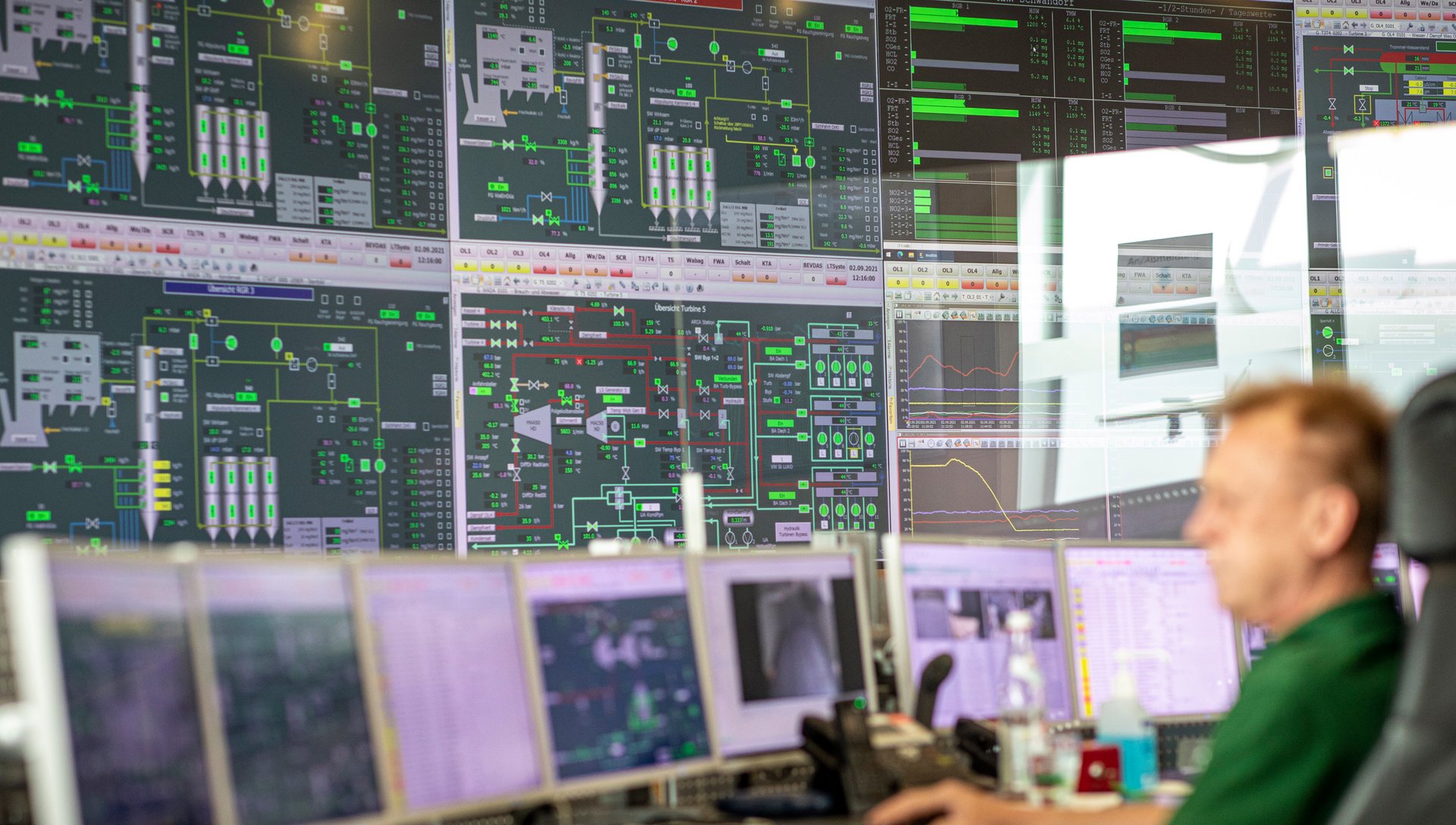 Blick auf einen Mitarbeitenden vor vielen Bildschirmen