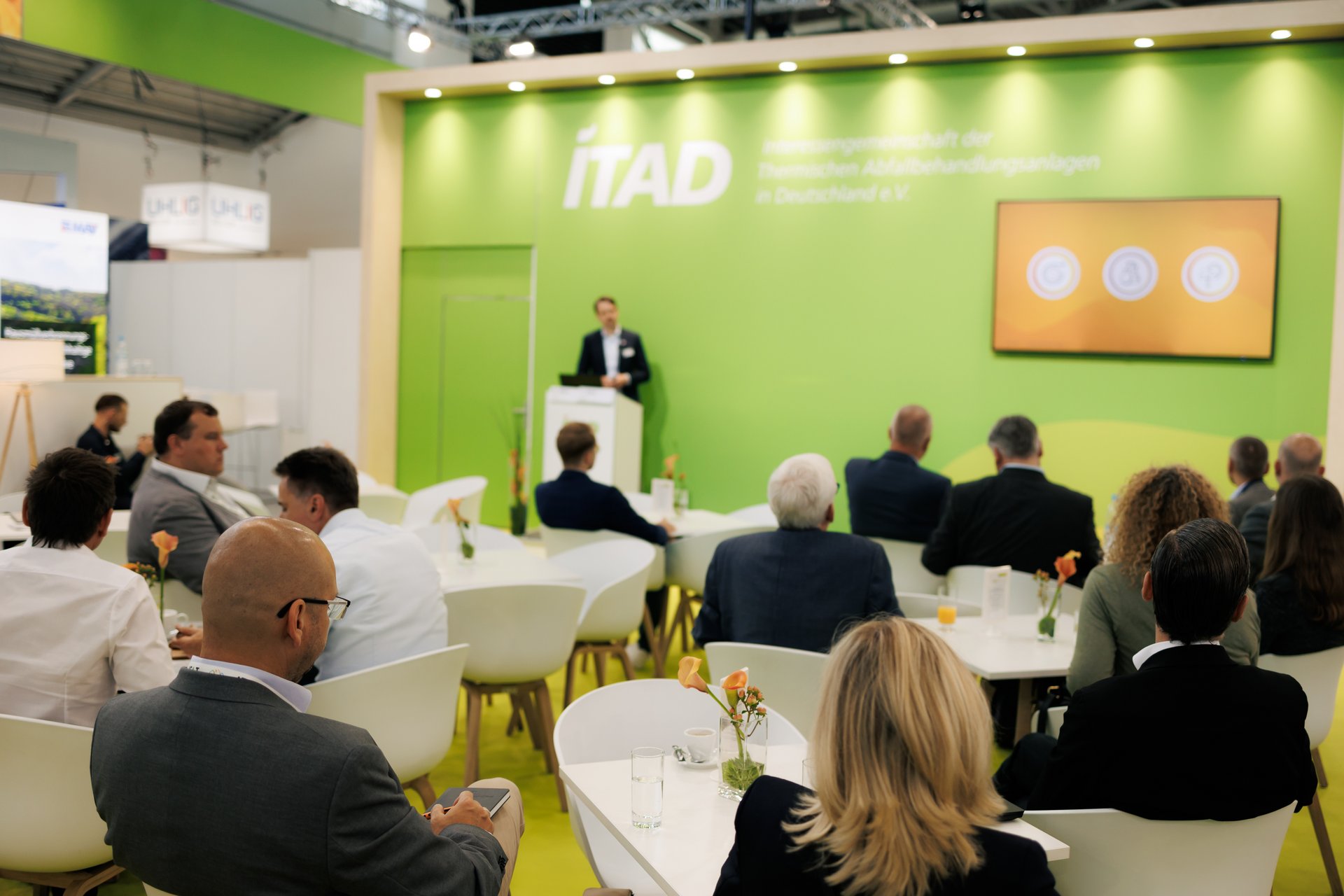 Menschen sehen einem Redner hinter Rednerpult zu