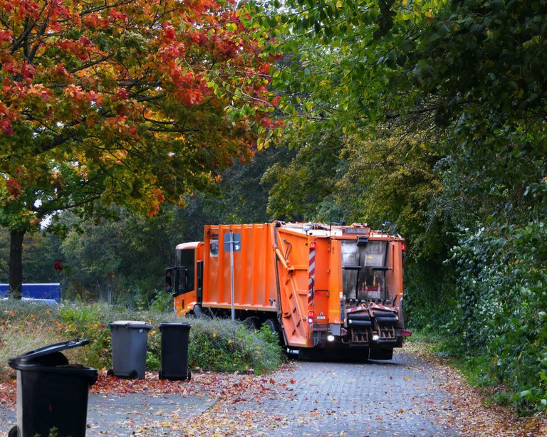 Großes, oranges Auto, welches Müll einsammelt